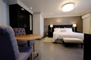 约翰内斯堡魔诱别墅酒店的酒店客房带一张床、一张桌子和椅子