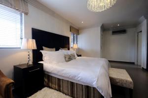 约翰内斯堡魔诱别墅酒店的卧室配有一张白色大床和吊灯。