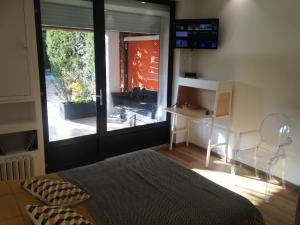 福卡尔基耶CHAMBRE CENTRE VILLE Coté soleil的一间卧室配有床、书桌和滑动玻璃门