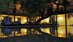 曼谷VILLA BANGKOK formerly VILLA PHRA SUMEN的一座带椅子和树的夜间游泳池