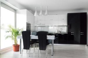 奥托佩尼Airport Residence - Apartment across from Otopeni Airport的厨房配有黑白橱柜和桌椅