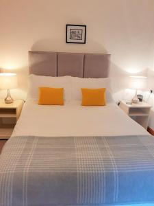 比尔斯韦尔斯Wye Cottage的一间卧室配有一张大床和两个橙色枕头
