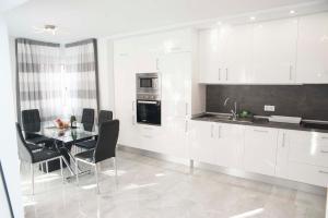 美洲海滩Playa de Las Americas Luxury Home的厨房配有白色橱柜和桌椅