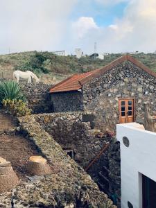 EreseCasita Pedro González的一座石头房子,后面有一只白马