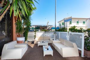西维尔诺瓦·马尔凯日光浴酒店 的庭院设有白色的沙发、桌子和棕榈树