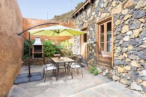 El Pinar del HierroHome2Book Charming Rustic House El Pinar & Wifi的庭院内桌椅和遮阳伞