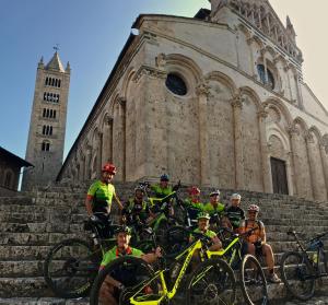 马萨马里蒂马Agriturismo Bike Hotel Podere Giarlinga的一群人骑着自行车,在教堂前走几步