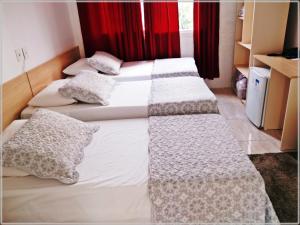 格拉瓦塔伊Hotel Anjos LTDA的带红色窗帘的客房内的3张单人床