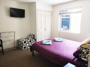 珀斯巴尔卡塔胜地度假屋的一间卧室配有一张床、一把椅子和电视