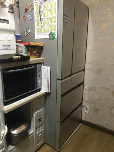 小樽Sunny house的厨房里配有不锈钢冰箱及微波炉
