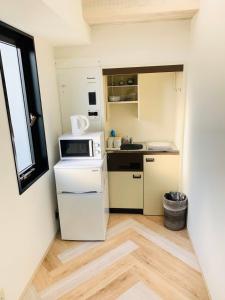 大阪WELLSTAY Honmachi的小厨房配有白色冰箱和窗户