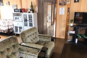 读谷村SMILE ONE GUEST HOUSE OKINAWA的客厅配有沙发、椅子和电视