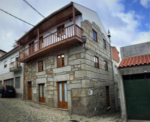塔布阿苏Casa Da Tia Em Tabuaço的一座石头建筑,上面设有一个阳台