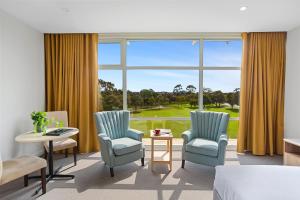 吉朗吉朗柏丽汽车旅馆 的酒店客房设有两把椅子、一张床和大窗户
