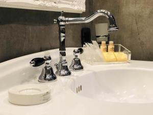 罗马圣B精品STB酒店的白色浴室水槽,配有铬面水龙头和化妆品