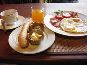 吉婆岛Cat Ba Bay Vision Hotel的一张桌子,上面放着两盘早餐食品和一杯橙汁