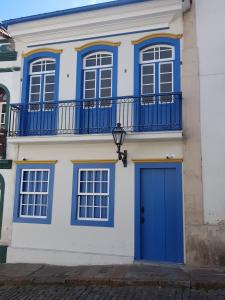 欧鲁普雷图Suíte Marília de Dirceu的拥有蓝色门和阳台的房子