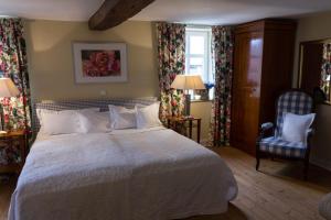 黑塞罗德罗曼蒂克罗森霍夫酒店的卧室配有一张白色大床和一把椅子