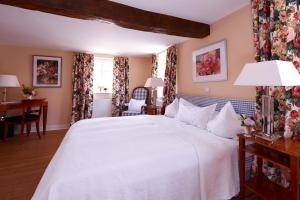 黑塞罗德罗曼蒂克罗森霍夫酒店的卧室配有一张白色大床和一张书桌