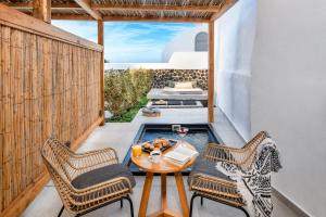 费拉卡里阿度假套房酒店 - 仅限成人入住的阳台的天井配有桌椅