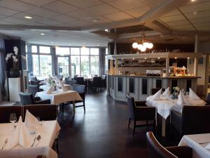 尼维莱特巴德尼维莱特巴德弗莱彻餐厅酒店的一间设有白色桌椅的餐厅和一间酒吧