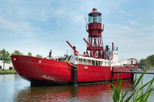 阿姆斯特丹Lightship Amsterdam的水中一艘红色和白色的船,有一座灯塔