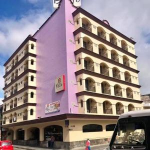 科尔多瓦Hotel Bello Cordoba的粉红色的建筑,旁边有一个钟