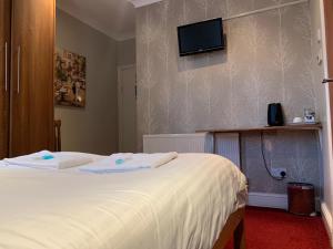 特威克纳姆图维克汉姆宾馆的一间卧室设有两张床,墙上配有电视。