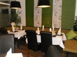 马克兰斯泰特罗森克朗茨餐厅酒店的用餐室配有带白色桌子和黑色椅子的桌子