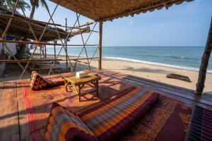 高兰Isara Lanta Beach Resort的海滩上设有一张沙发和一张桌子,大海上设有