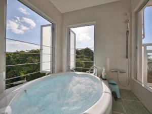 本部星之露台本部山里酒店的带浴缸的浴室,设有大窗户