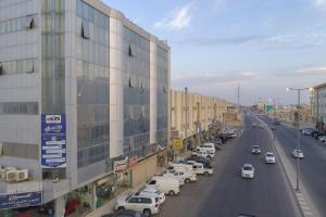 布赖代Al Eairy Apartment-Alqaseem 4的一条城市街道,汽车停在大楼旁边