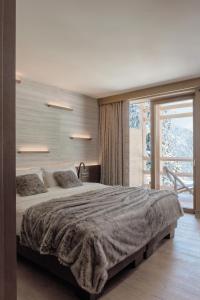 平佐洛Lefay Resort & SPA Dolomiti的一间卧室设有一张大床和一个大窗户