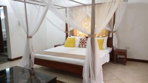 布韦朱Villa Oman的一间卧室配有一张带黄色枕头的天蓬床