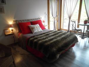Le NoyerLa Buissonnière的一间卧室配有一张带红色枕头的大床