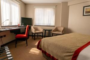 内乌肯内乌肯塔酒店的酒店客房,配有一张床、一张桌子和椅子