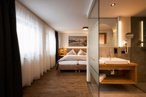 富尔普梅斯Hotel Brugger的浴室设有床、水槽和镜子