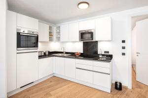 迈斯霍芬lake and mountains appartements的白色的厨房配有白色橱柜和黑色台面