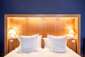 利尔Hotel Hof van Aragon的一张带两个白色枕头和木制床头板的床
