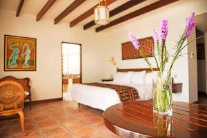 帕拉卡斯拉哈西恩德巴伊亚帕拉卡斯酒店的一间房间,配有一张床和一个花瓶,花朵花朵在桌子上