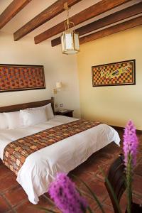 帕拉卡斯拉哈西恩德巴伊亚帕拉卡斯酒店的配有一张床和紫色鲜花的酒店客房