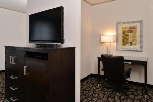 莱克伍德Holiday Inn Express & Suites Tacoma South - Lakewood, an IHG Hotel的酒店客房配有书桌、电视和椅子。