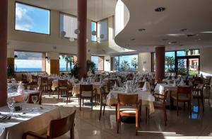 蓬塔德尔加达Monte Mar Palace Hotel的餐厅设有白色的桌椅和窗户。