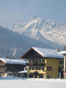 柯尼希斯湖畔舍瑙Sporthotel Schönau am Königssee的一座有雪覆盖的山的建筑