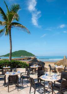 马萨特兰Pueblo Bonito Mazatlan Beach Resort - All Inclusive的一个带桌椅的海滩和棕榈树