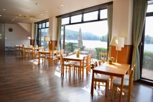 信浓野尻湖度假酒店的餐厅设有桌椅和大窗户。