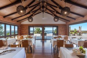 Lalomanu阿迦珊瑚礁度假村及Spa酒店的餐厅设有白色的桌椅,享有海景。