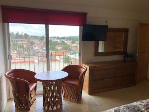 La Manzanilla de la PazCHIFLON VILLAS的客房设有桌椅和大窗户。