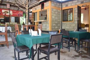 Boma la Ngombe彩虹行政山林小屋的用餐室配有2张绿色的桌椅
