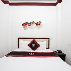 岘港布朗槟2号酒店的一间卧室配有一张带白色床罩和防过敏床罩的床